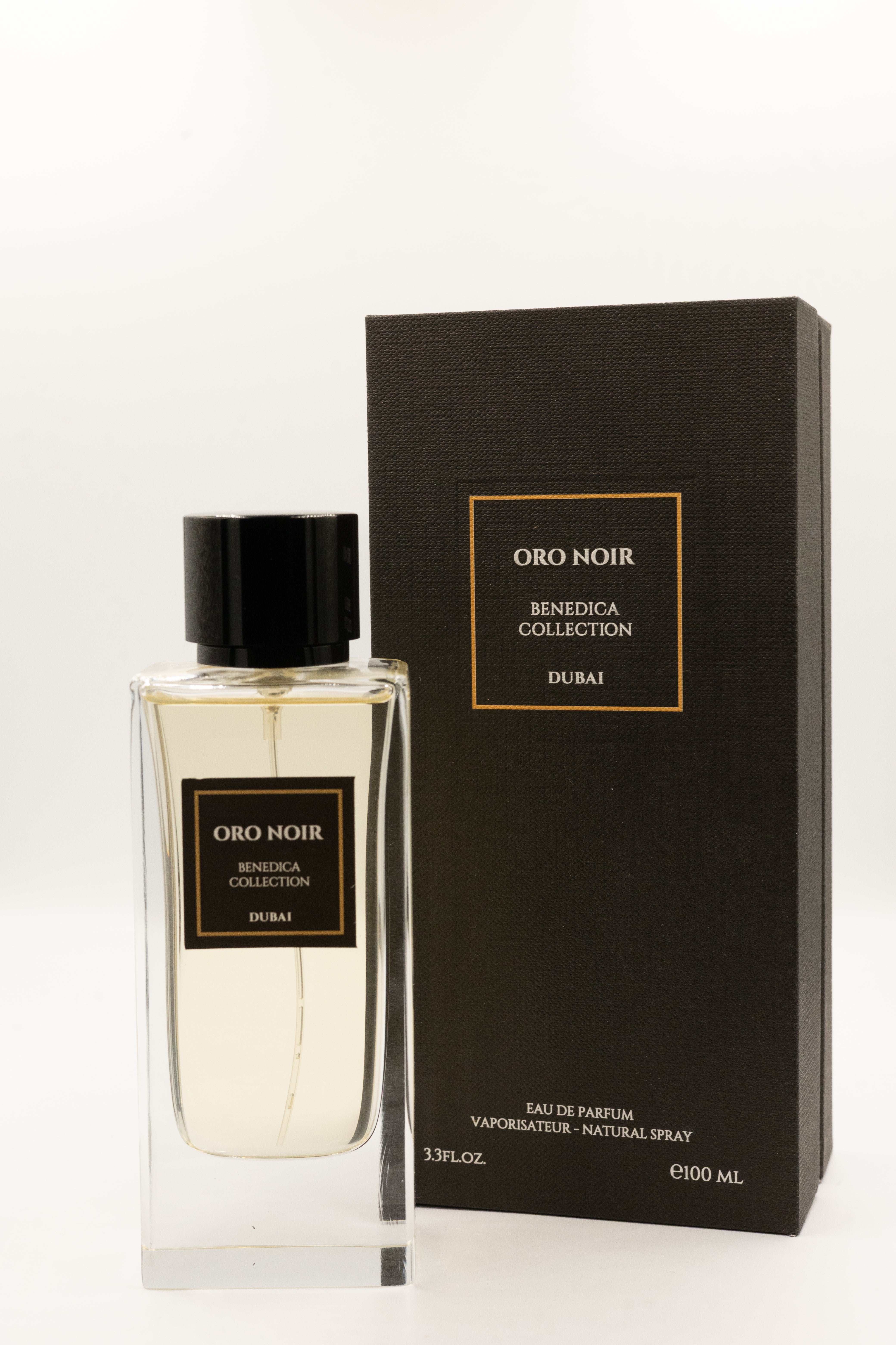 A clear BENEDICA ORO NOIR UNISEX EDP bottle from BENEDICA COLLECTION with a light liquid and black cap stands by its matching black and gold box, offering a luxurious unisex fragrance experience.