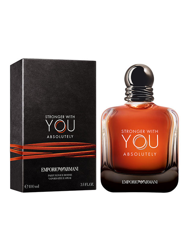 A bottle of GIORGIO ARMANI ARMANI STRONGER WITH YOU ABSOLUTELY MEN, filled with amber liquid and featuring sensual sweet and oriental woody notes, is displayed beside its black and orange box, both labeled with the product name.