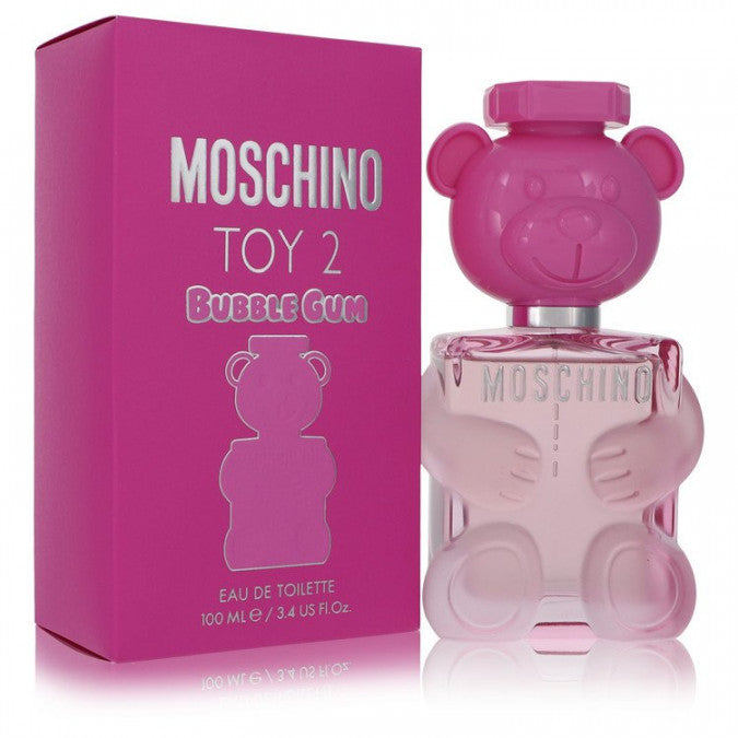 A pink box labeled MOSCHINO TOY 2 BUBBLE GUM EDT WOMEN stands next to a clear teddy bear-shaped perfume bottle with a pink cap, both by MOSCHINO, reflecting the fragrance’s sweet, playful character and fruity twist.